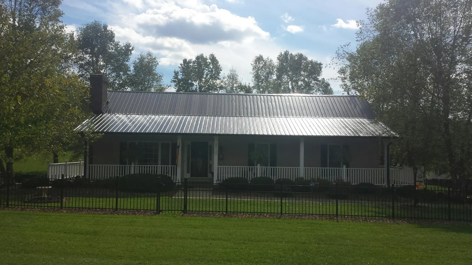 Gray metal roof on a brick ranch with a full width front porch — Gutter Guard Installation work by our crew in Clearfield