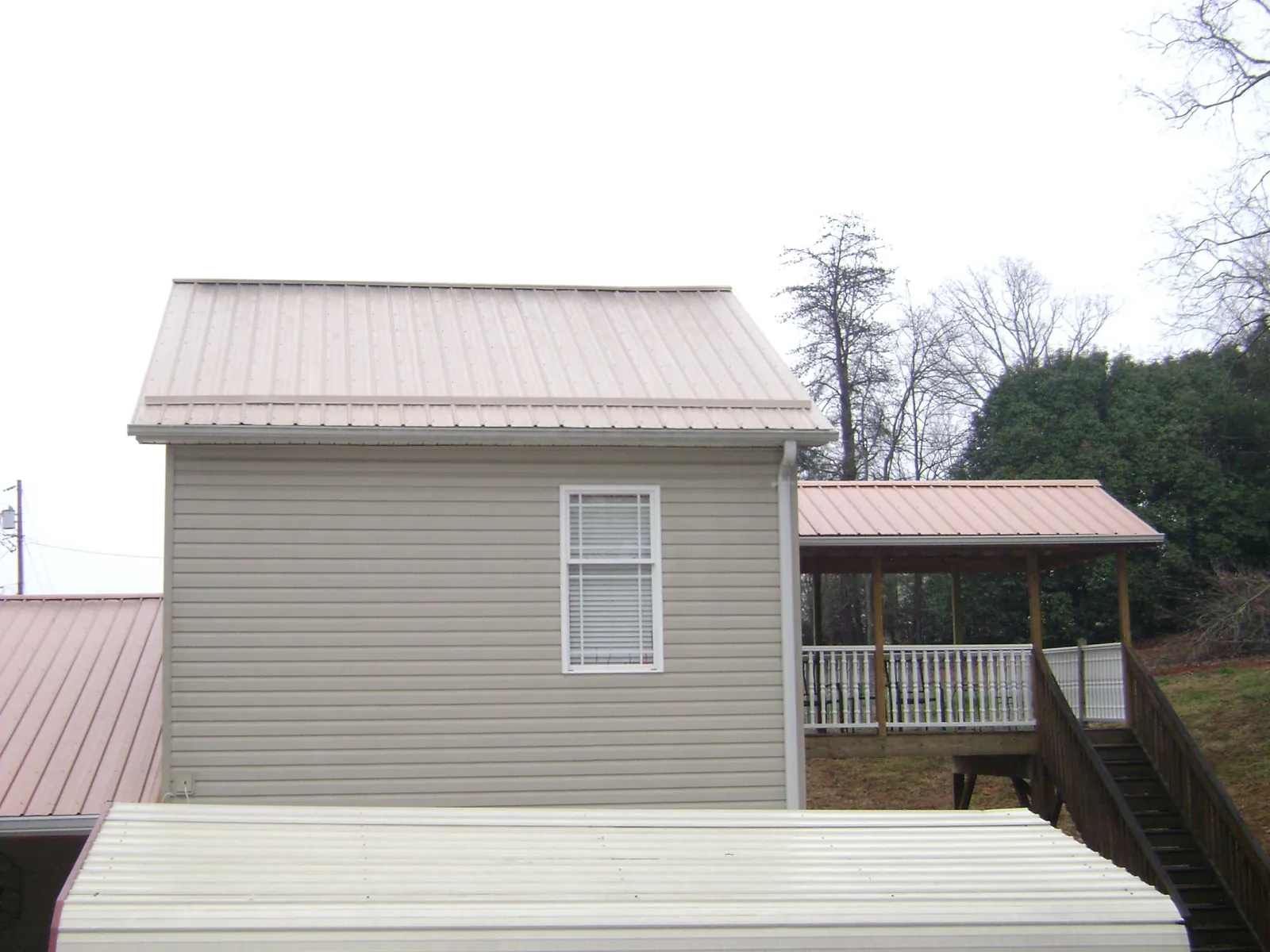 Tan metal roofs on a two story addition and attached porch, from a Roof Replacement job in Clearfield