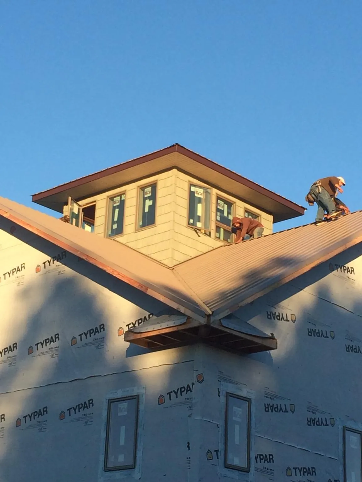 Roofers working around a rooftop cupola on a new metal roof at sunset — Roof Waterproofing in Clearfield by Roofing Brothers